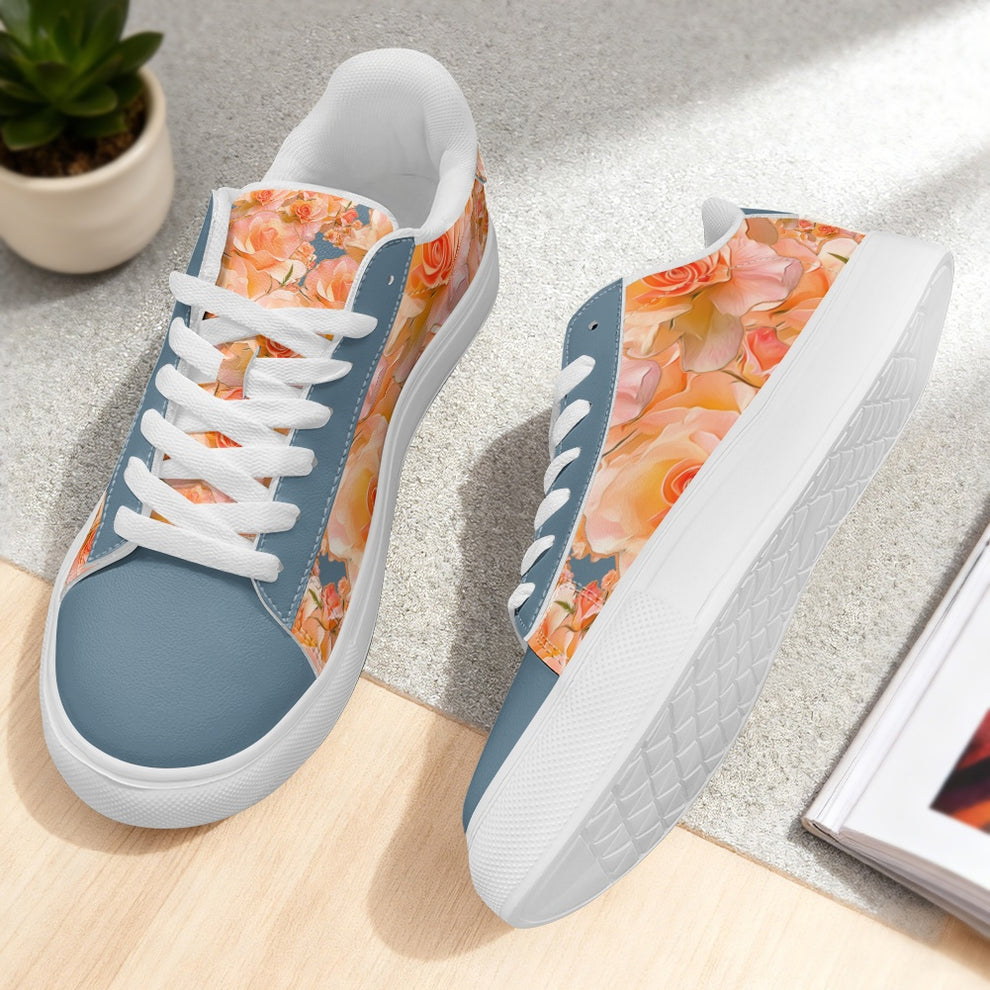 Low-top sneakers with dusty blue panels and peach floral patterns, featuring white laces and soles. Shown on a neutral surface with a potted plant.