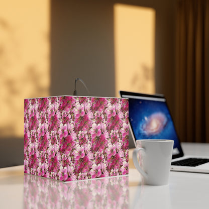 Square bedside lamp featuring pink floral art sitting on a white desk next to a ceramic mug and a laptop, illuminated by warm sunlight.