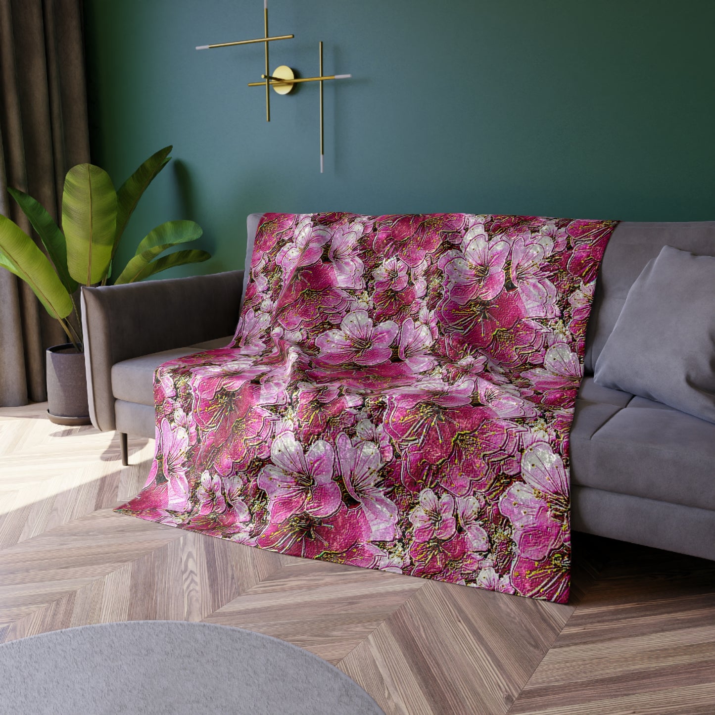 Crushed velvet blanket with a vibrant pink and white cherry blossom floral pattern, shown draped over a grey sofa.