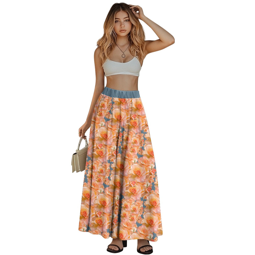 A woman stands against a white background wearing a high-waisted floor-length maxi skirt with a vibrant apricot and peach rose pattern. The skirt features a wide, slate-blue waistband and a flowing. A-line silhouette. 