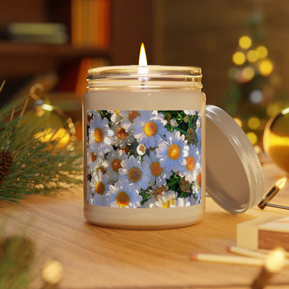 A lit Sun-Kissed Meadow scented candle in a clear glass jar with a white lid. The label features a high-density print of white and yellow daisies. The candle sits on a wooden table in a warm, cozy room with soft holiday bokeh lights and pine needles in the background.