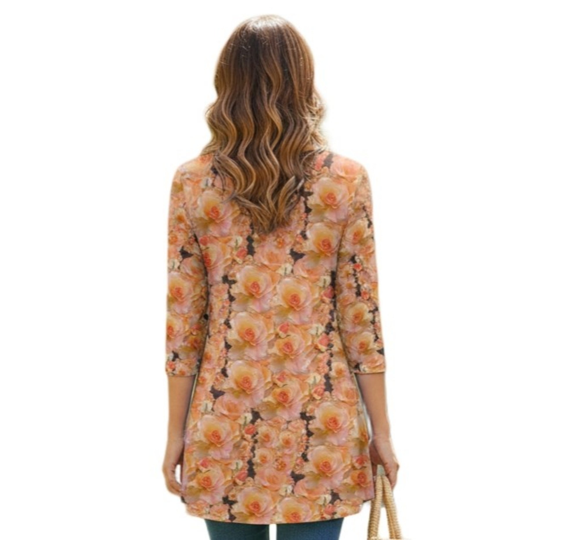 A back view of a woman with long, wavy blonde hair wearing a tunic-style top. The entire back of the garment features a vibrant, all-over print of large, peach-colored roses. The top has three-quarter length sleeves and a flared hem that falls to the upper thigh.