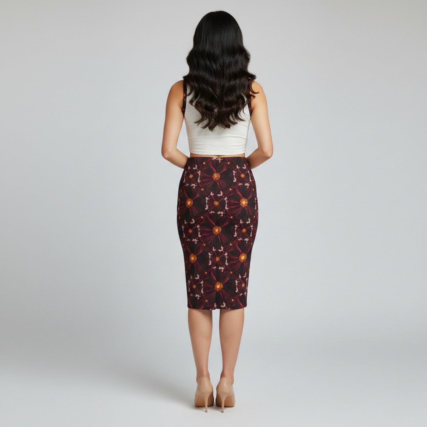 Back view of a woman with long wavy hair wearing a white crop top and floral midi skirt. 
