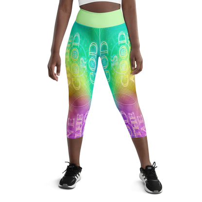 Front view of a person wearing rainbow gradient capri leggings with a neon "GOD IS GOOD" typography print and a light green waistband.mockup