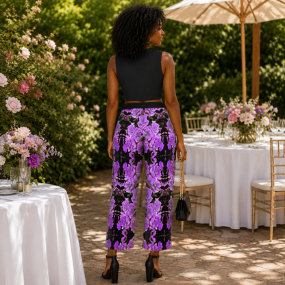 Rear view of the Argamon high-rise cropped flare pants in a purple floral emboss pattern, styled with a black crop top in a lush garden setting.