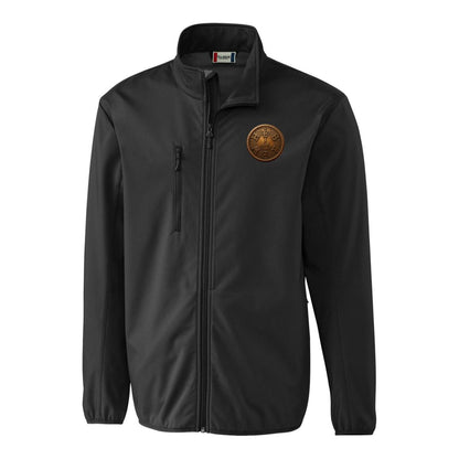 Front view of the black Clique Men's Trail Softshell Jacket with a bronze emblem on the left chest, isolated on a white background.