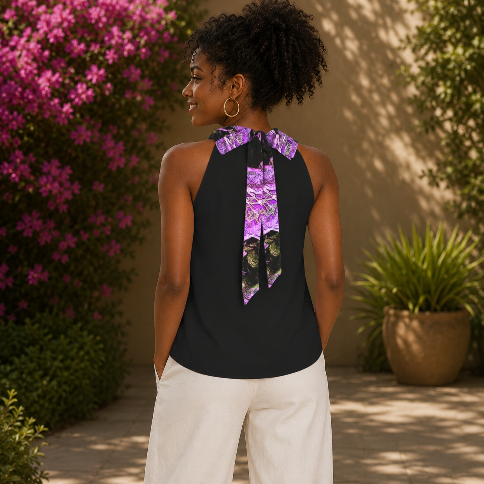 Rear view of a woman wearing the black mock-neck blouse, showcasing the elegant purple floral tie-back ribbon detail.