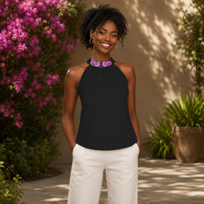 A smiling woman wearing the Argamon black sleeveless mock-neck blouse with a purple floral collar, paired with white trousers.