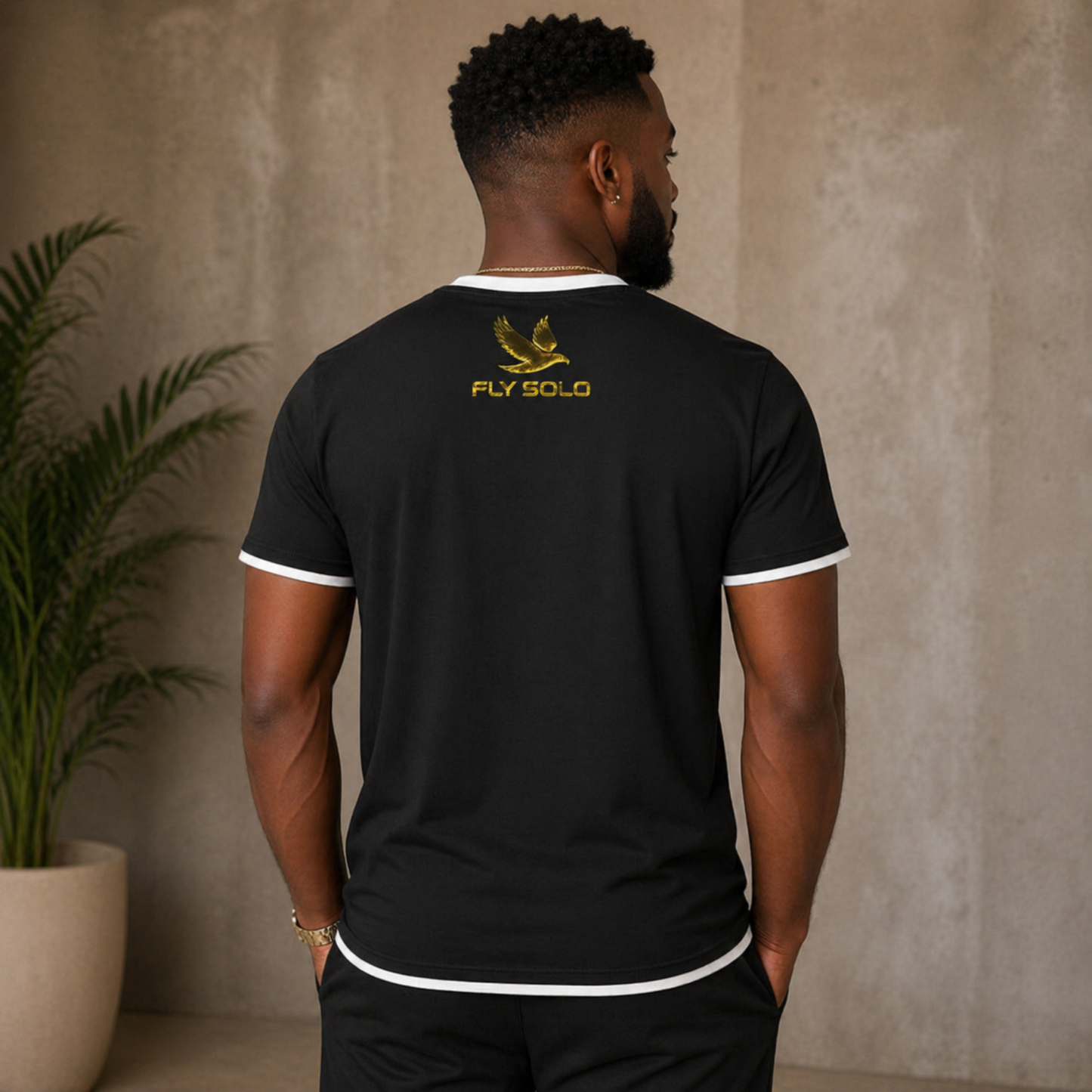 Back view of the black Fly Solo ringer tee with white trim, highlighting the golden eagle emblem and brand name on the upper back.