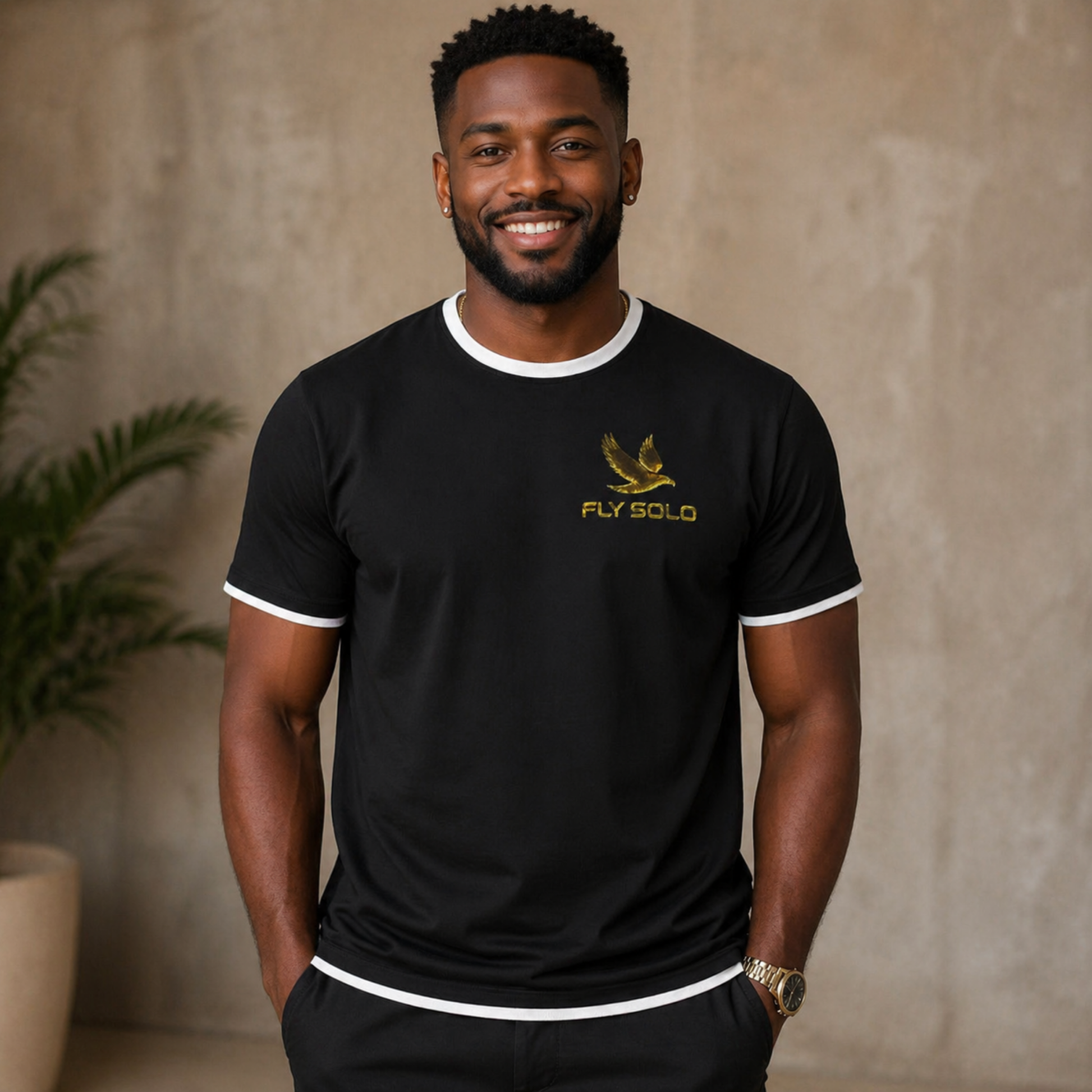 A man wearing the Fly Solo black ringer tee with white neck and sleeve trim, featuring the gold "Fly Solo" bird logo on the chest.