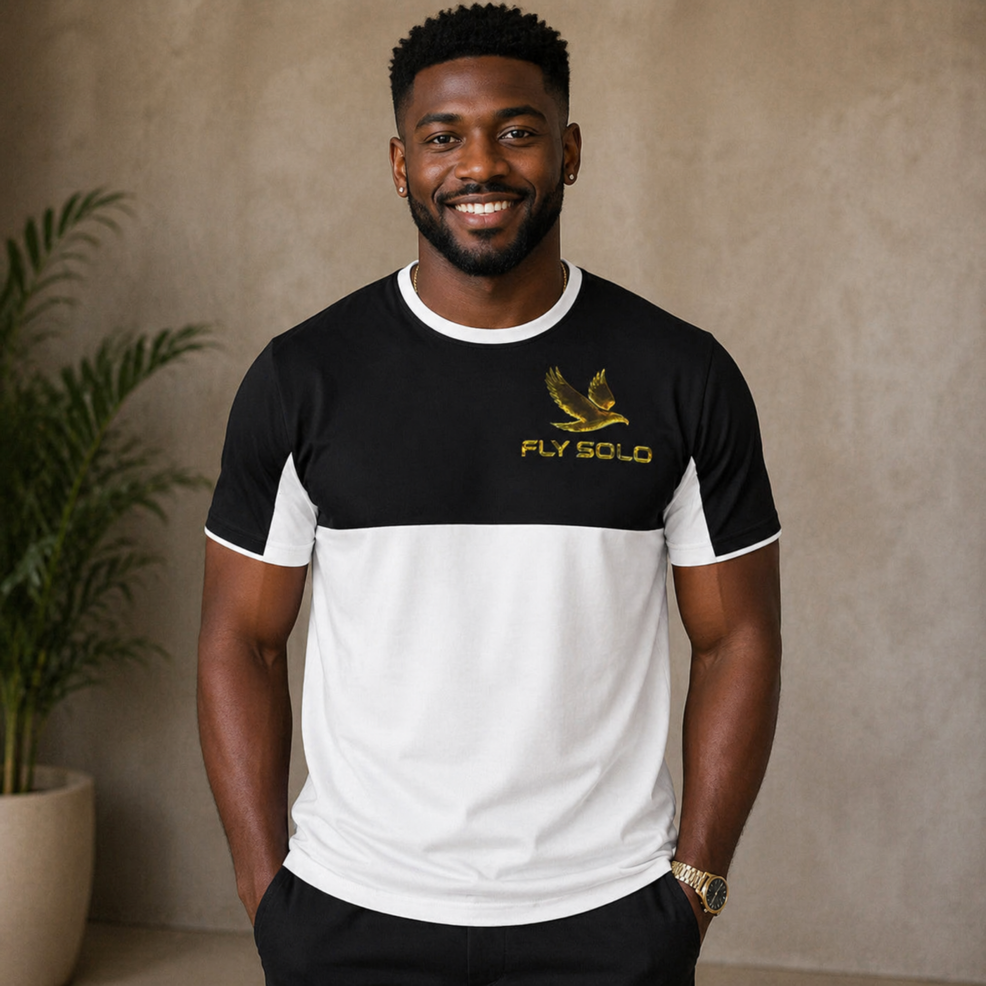 A man wearing the Fly Solo split-panel tee with a black upper half and white lower half, featuring a gold bird logo on the chest.