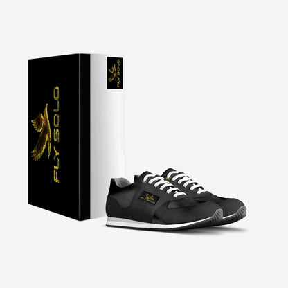 A pair of black and white men’s Fly Solo walking sneakers next to their custom black and gold designer shoe box.