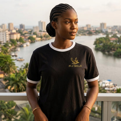 Front view of the Fly Solo ringer cotton tee worn by a woman on a balcony overlooking a coastal city skyline.