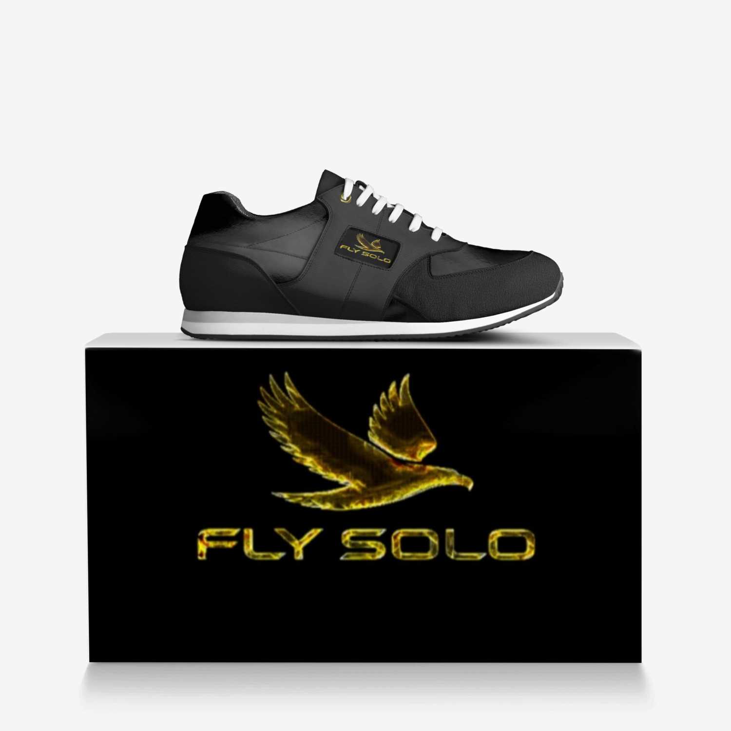 Close-up shot of the Fly Solo golden bird logo and brand name embossed on a black leather panel of the shoe.