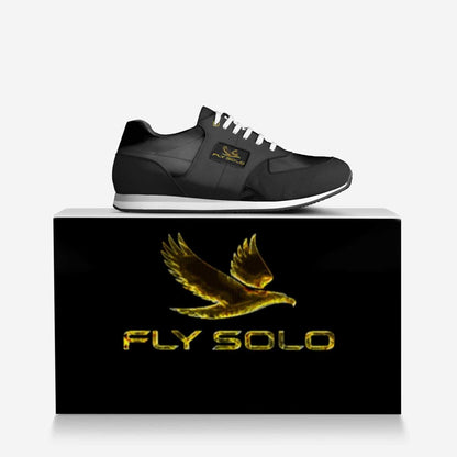 Close-up shot of the Fly Solo golden bird logo and brand name embossed on a black leather panel of the shoe.