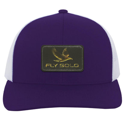 Front product shot of the deep purple Fly Solo trucker hat with white mesh panels and golden "Fly Solo" branding.