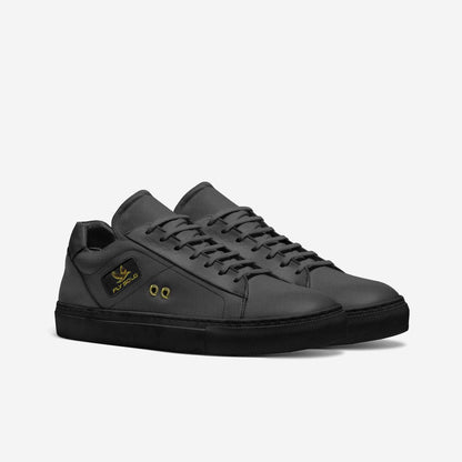 A pair of women's all-black Fly Solo sporty tennis style sneakers in dark grey leather, featuring a small gold eagle logo and brass lace eyelets.