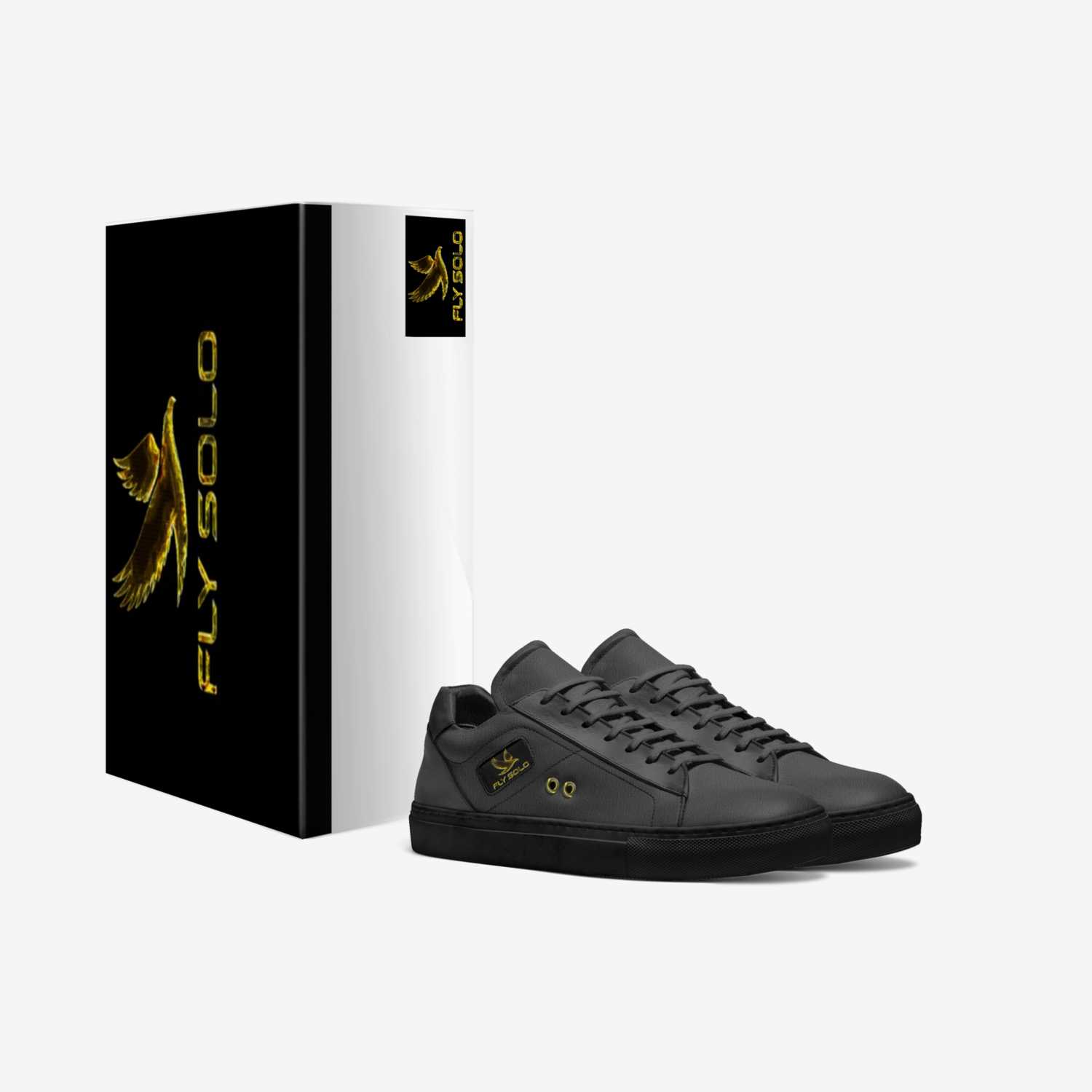An oblique perspective shows a pair of women's Fly Solo black low-top sneakers and the shoebox, both featuring the gold eagle logo. Dark grey leather and white accents.