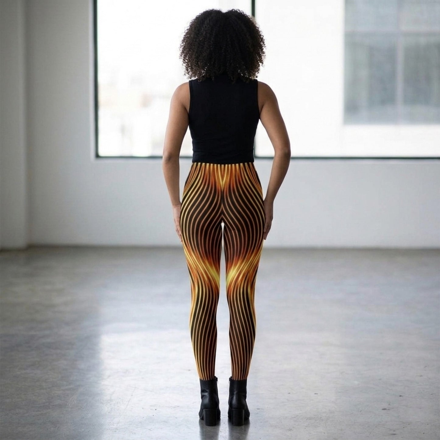 Rear view of a model in a bright, minimalist studio showcasing the orange and black eternal flame pattern on the high-stretch tights.