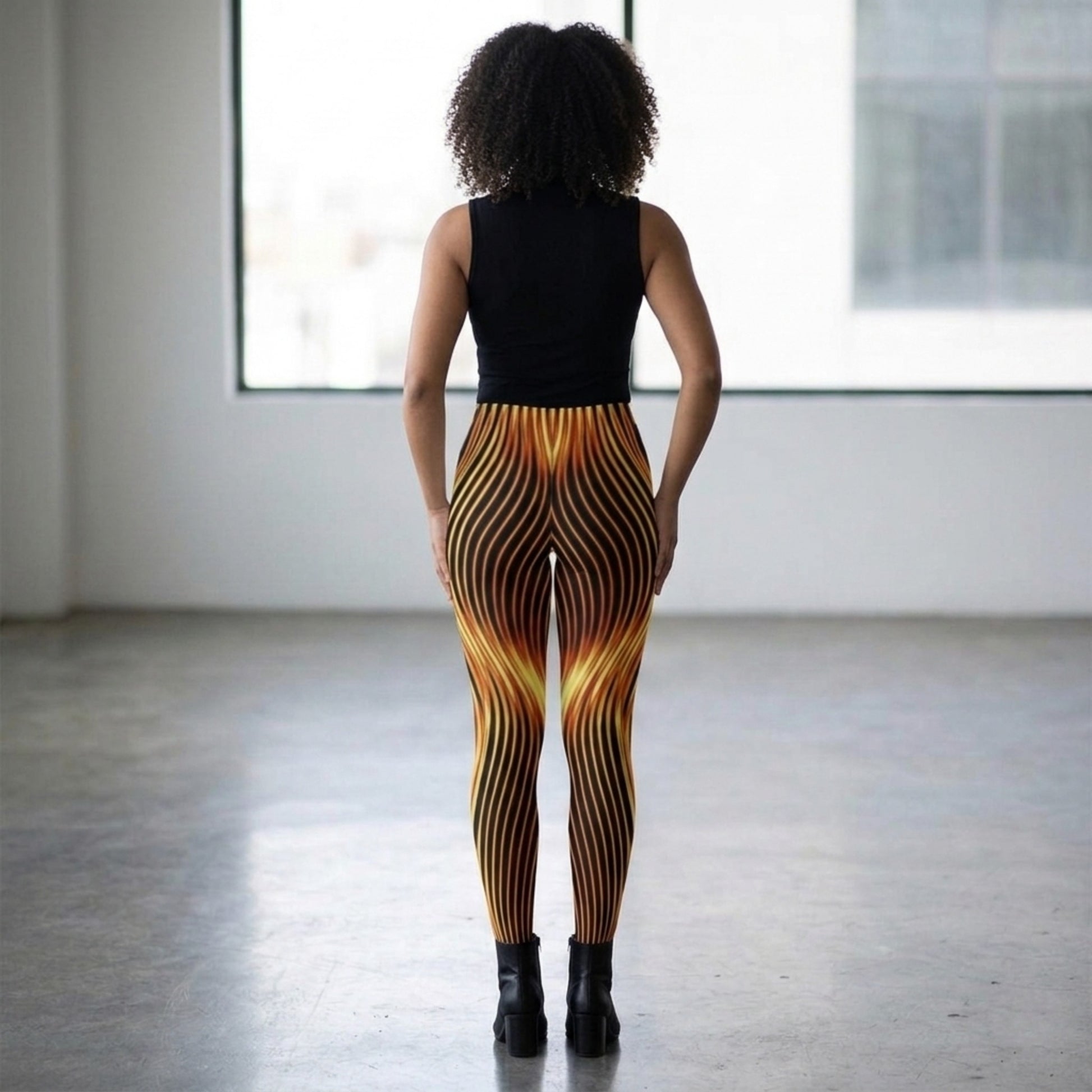 Rear view of a model in a bright, minimalist studio showcasing the orange and black eternal flame pattern on the high-stretch tights.