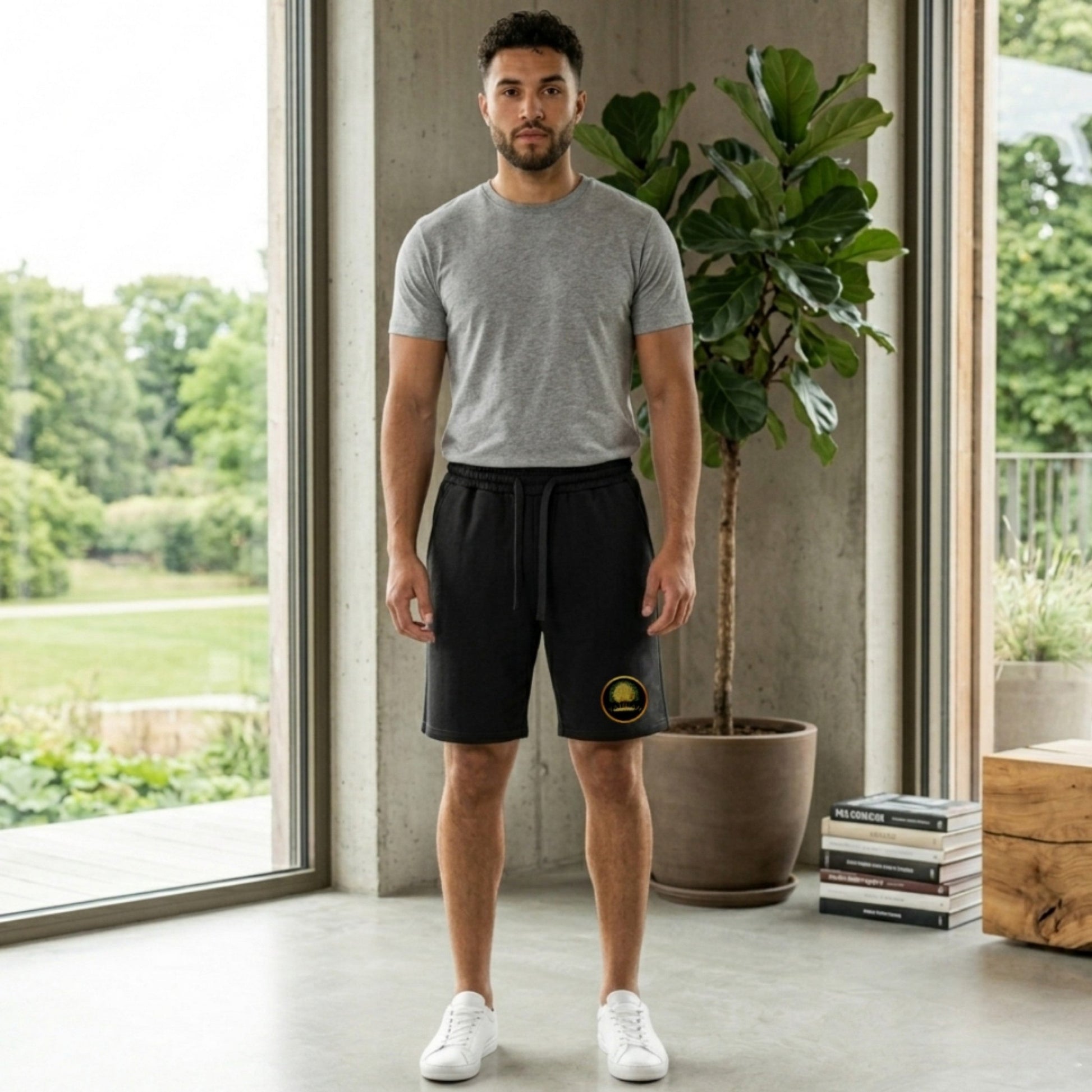 Front view of a man wearing black Yahuah Tree of Life heavyweight sweat shorts featuring a gold circular graphic on the leg and back pocket.
