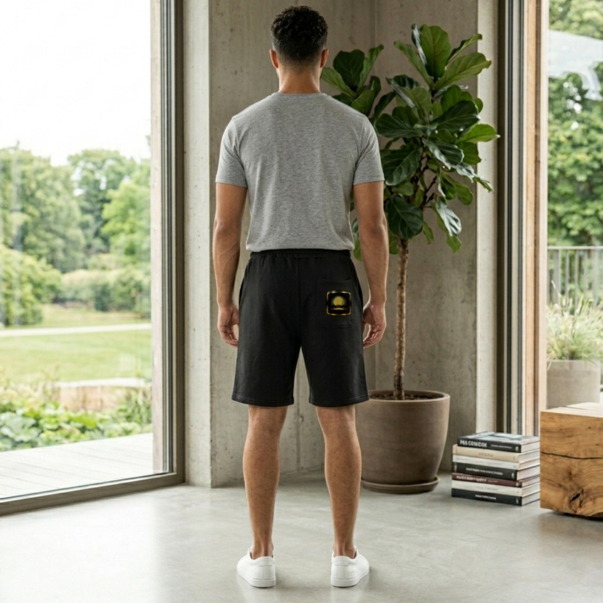 Back view of a man wearing black Yahuah Tree of Life heavyweight sweat shorts featuring a gold circular graphic on the leg and back pocket.