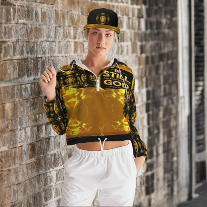 Woman poses by brick wall wearing a black and gold patterned "Be Still" crop jacket and matching cap, with white pants.