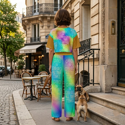 Back view of a woman and two French Bulldogs on a cobblestone street, showcasing a colorful tie-dye outfit with "God is Good All the Time" text.