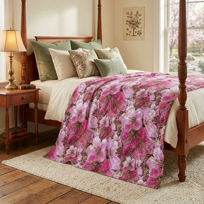 Crushed velvet blanket with a vibrant pink and white cherry blossom floral pattern, shown draped over a bed.
