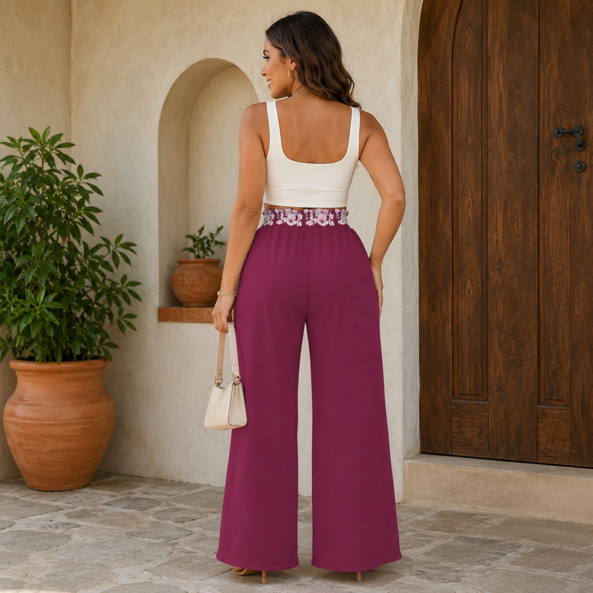 Back view of a woman styling the Sakura Symphony high-waist wide-leg pants, showcasing the floral smocked waistband and white top.