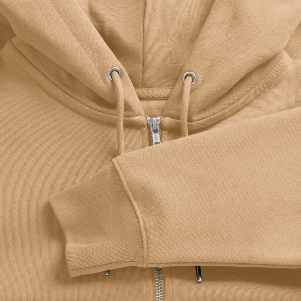Detailed close-up of an off-white organic zip hoodie, focusing on the silver metal zipper, matching drawstrings, and heavy-knit cotton fabric texture.