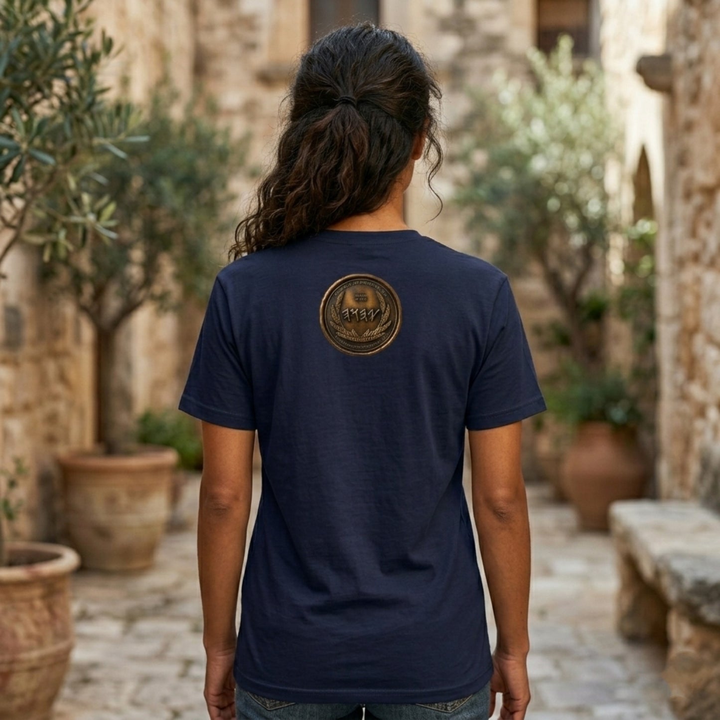 Back view of a navy blue oversized heavyweight t-shirt displaying a circular antiqued bronze medallion
