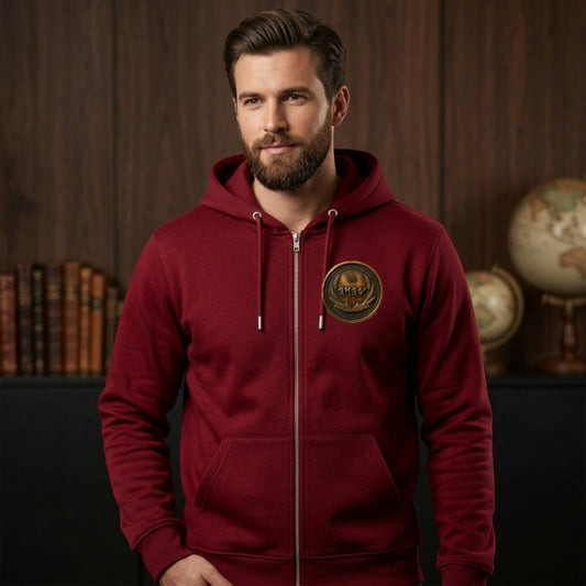 Front view of a bearded man wearing a burgundy organic zip hoodie featuring a circular antiqued bronze medallion chest emblem.
