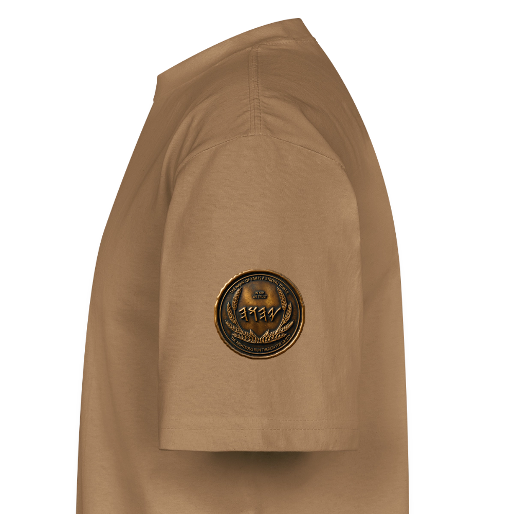 Side profile view of a tan oversized heavyweight t-shirt, highlighting a circular antiqued bronze symbolic medallion on the right sleeve fabric.