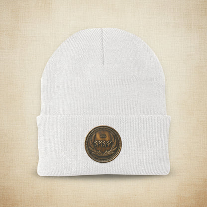 Detailed view of the intricate antiqued bronze symbolic medallion on a white knit cuffed beanie.