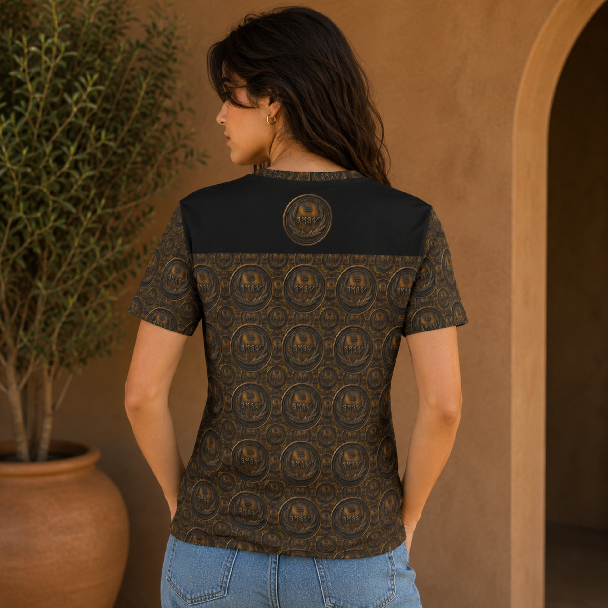 Back view of a woman wearing the antiqued bronze tee, highlighting the repeating coin pattern and upper black panel with a seal.
