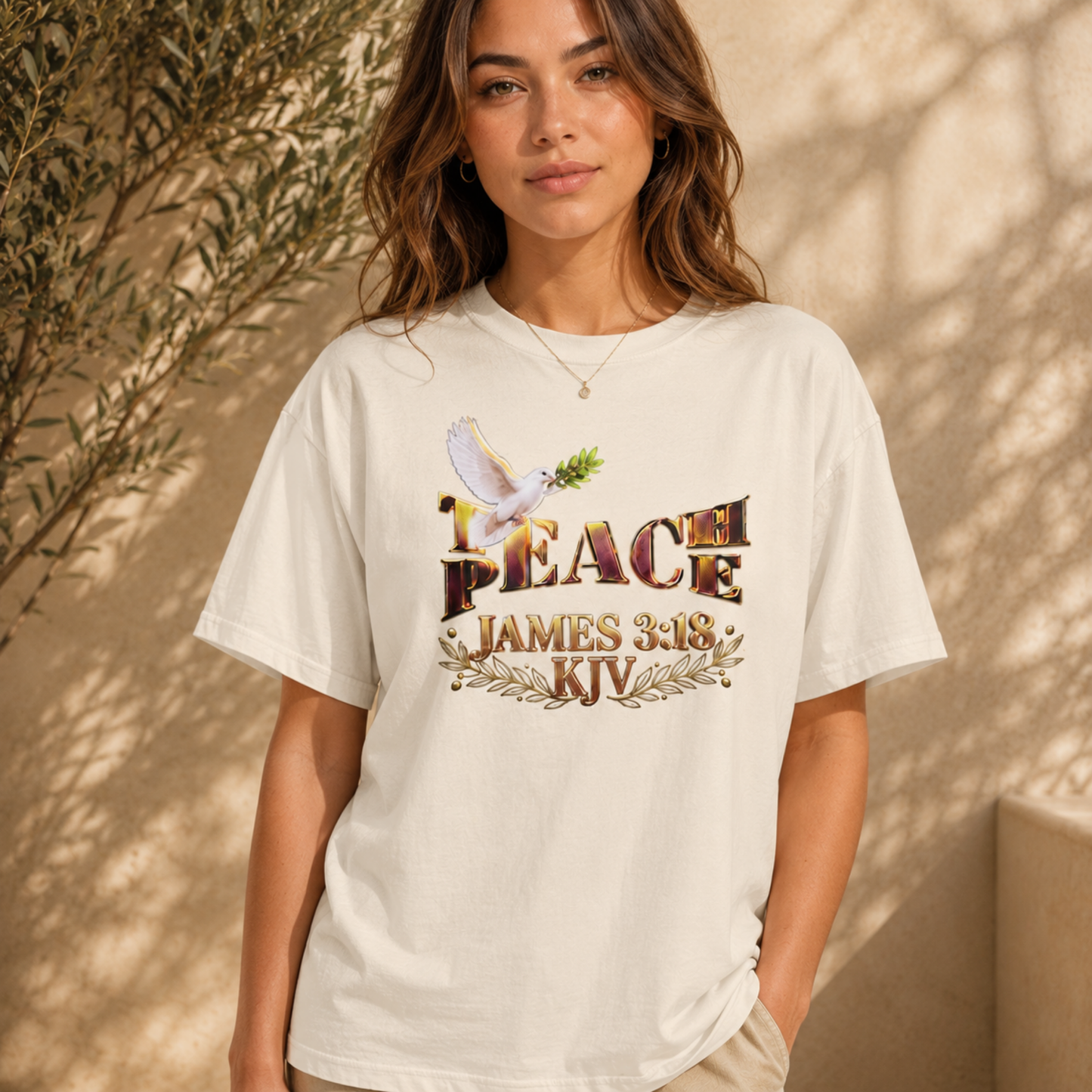 woman showcasing the sand Teach Peace James 3:18 oversized graphic tee in natural sunlight.