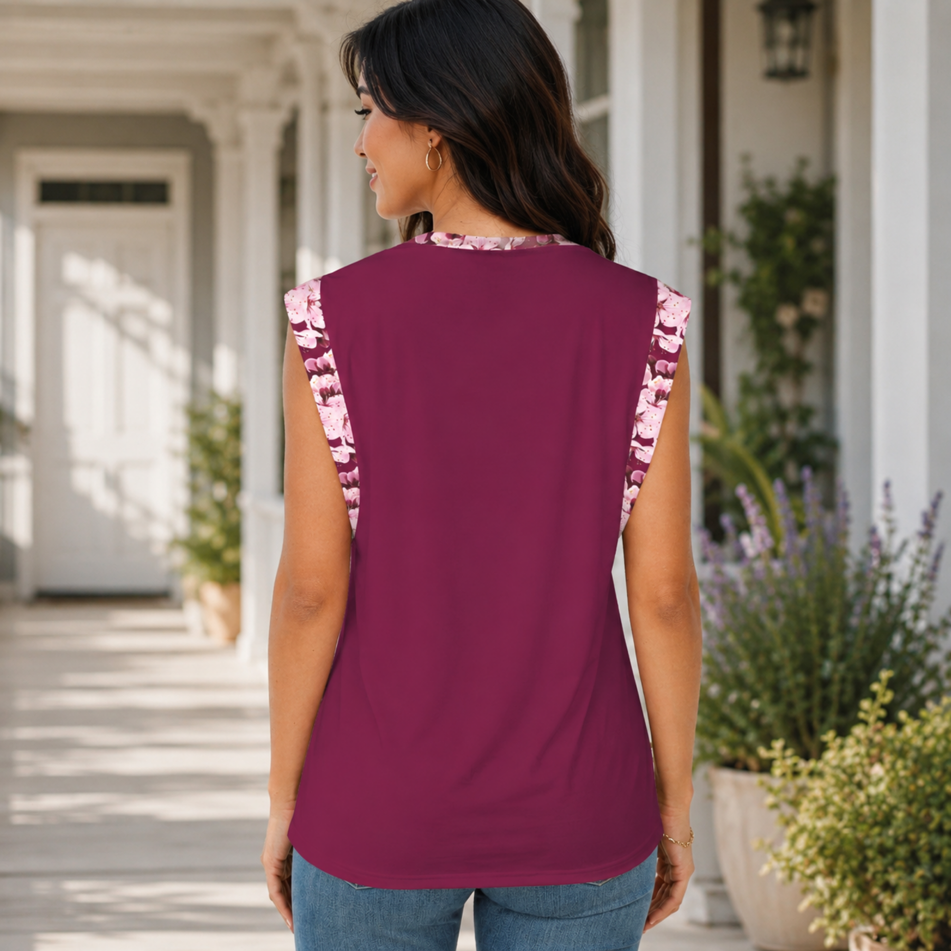 Back view of a woman on a porch wearing a maroon cap-sleeve t-shirt with pink cherry blossom floral accents on the sleeves and collar.
