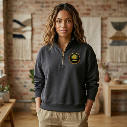 Front view of a woman in a charcoal heavyweight half-zip sweatshirt featuring the gold Yahuah Tree of Life emblem on the chest and a large back graphic.