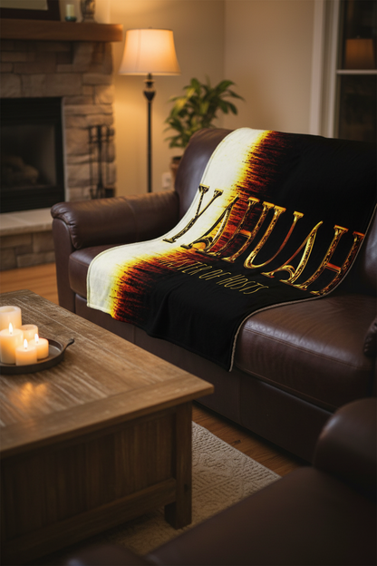 Premium Yahuah Master of Hosts sublimation throw blanket draped over a brown leather couch in a cozy, candlelit living room setting.